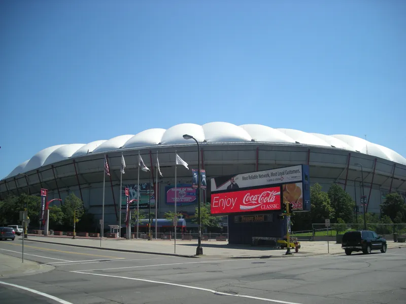 The Metrodome exterior on a summer day, its white inflated roof rising over the entrance plaza