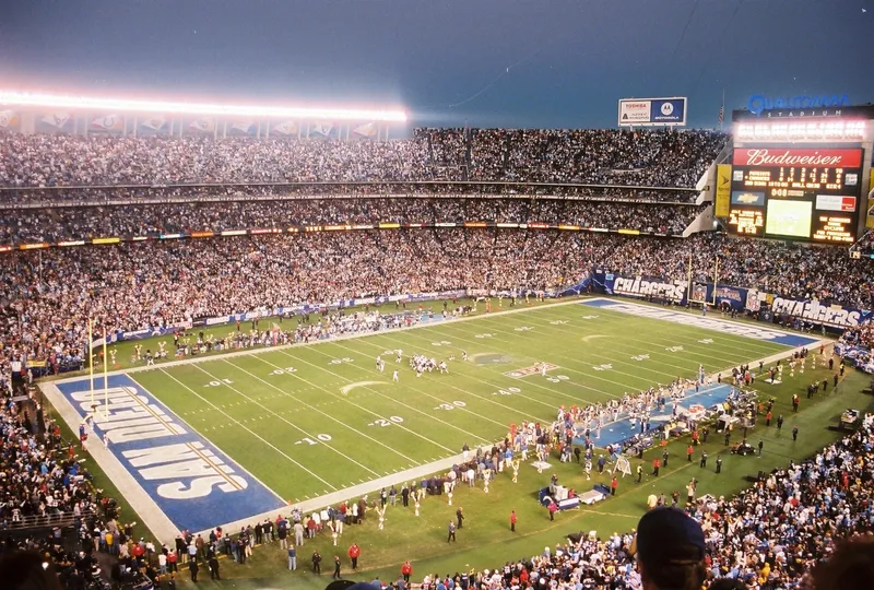 Wide view of a packed Qualcomm Stadium under the lights, the Chargers end zone and scoreboard in view